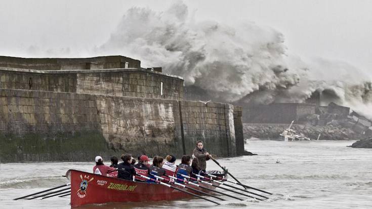 Argazkia: Arraunlariak entrenatzen eta atzean olatu ikaragarria barra puntan lehertzen